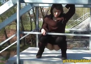 Brave MILF is pissing in a public place on the camera